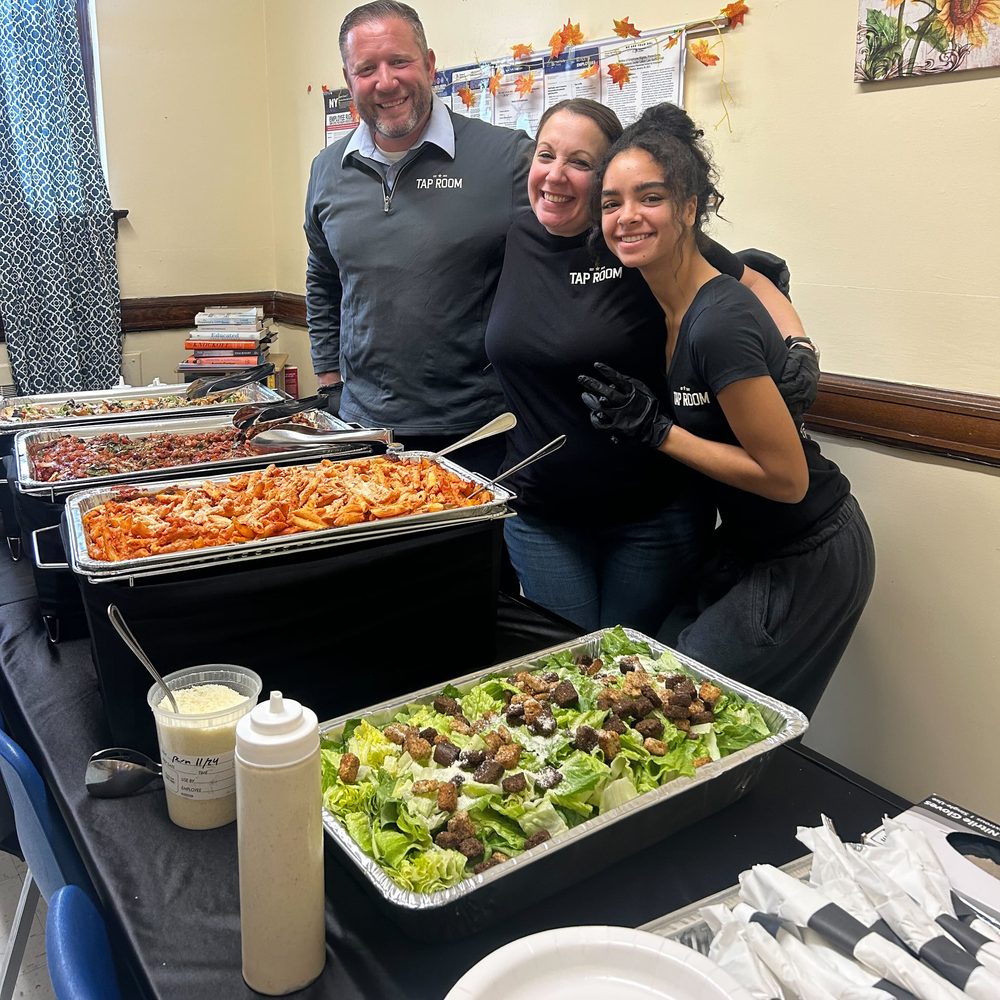 Tap Room staff serving pasta and salad in a school faculty room.